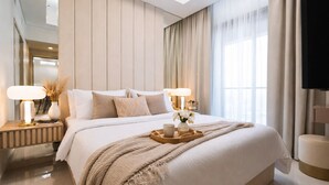 A modern hotel room with a large bed, bedside lamps, a tray with a cup and flowers, and a TV on the wall. - Keyrock Living - Oasis with Balcony View (Dubai)
