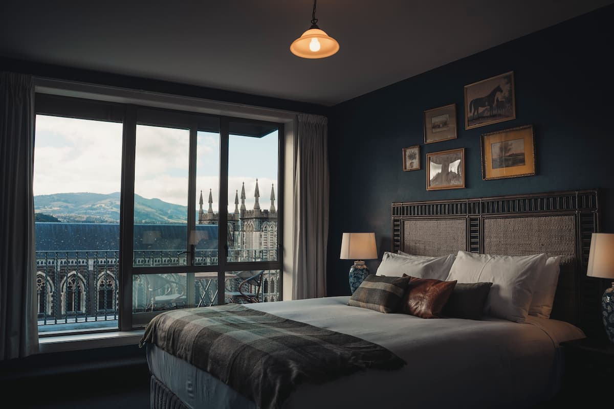 Ein Schlafzimmer mit großem Fenster, einem Bett mit Kissen und einem Kopfteil mit gerahmten Bildern.