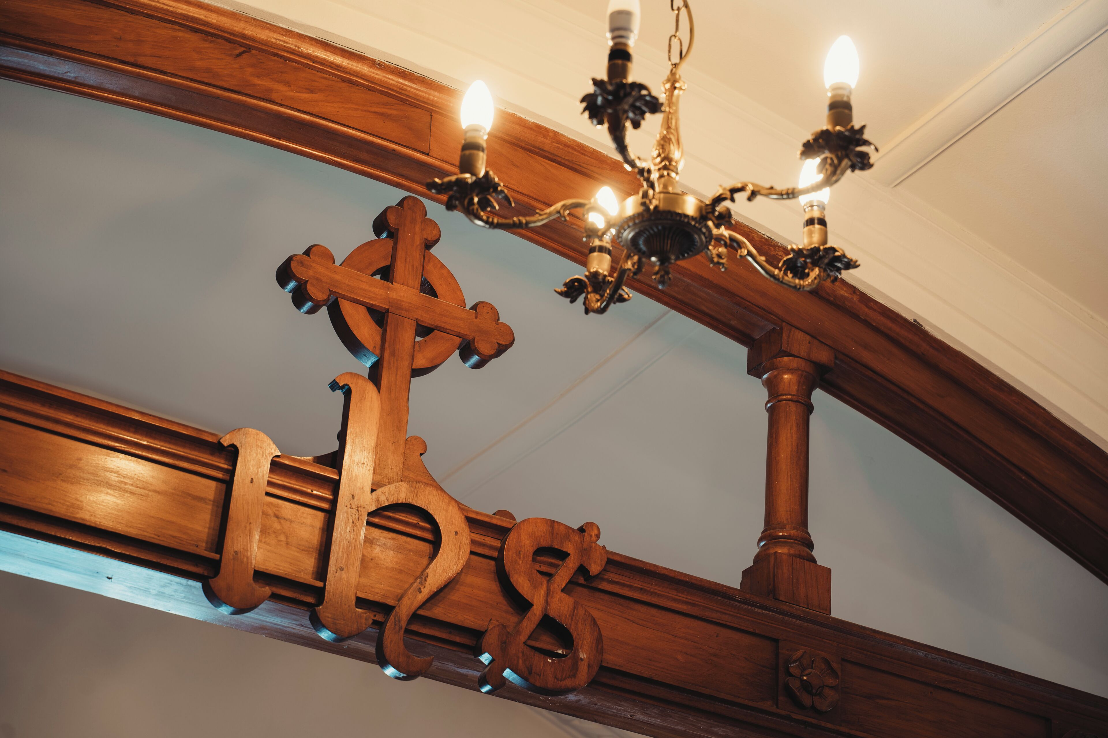 Eine Holzbalkendecke mit einem Chandelier und einem hölzernen Kreuz.