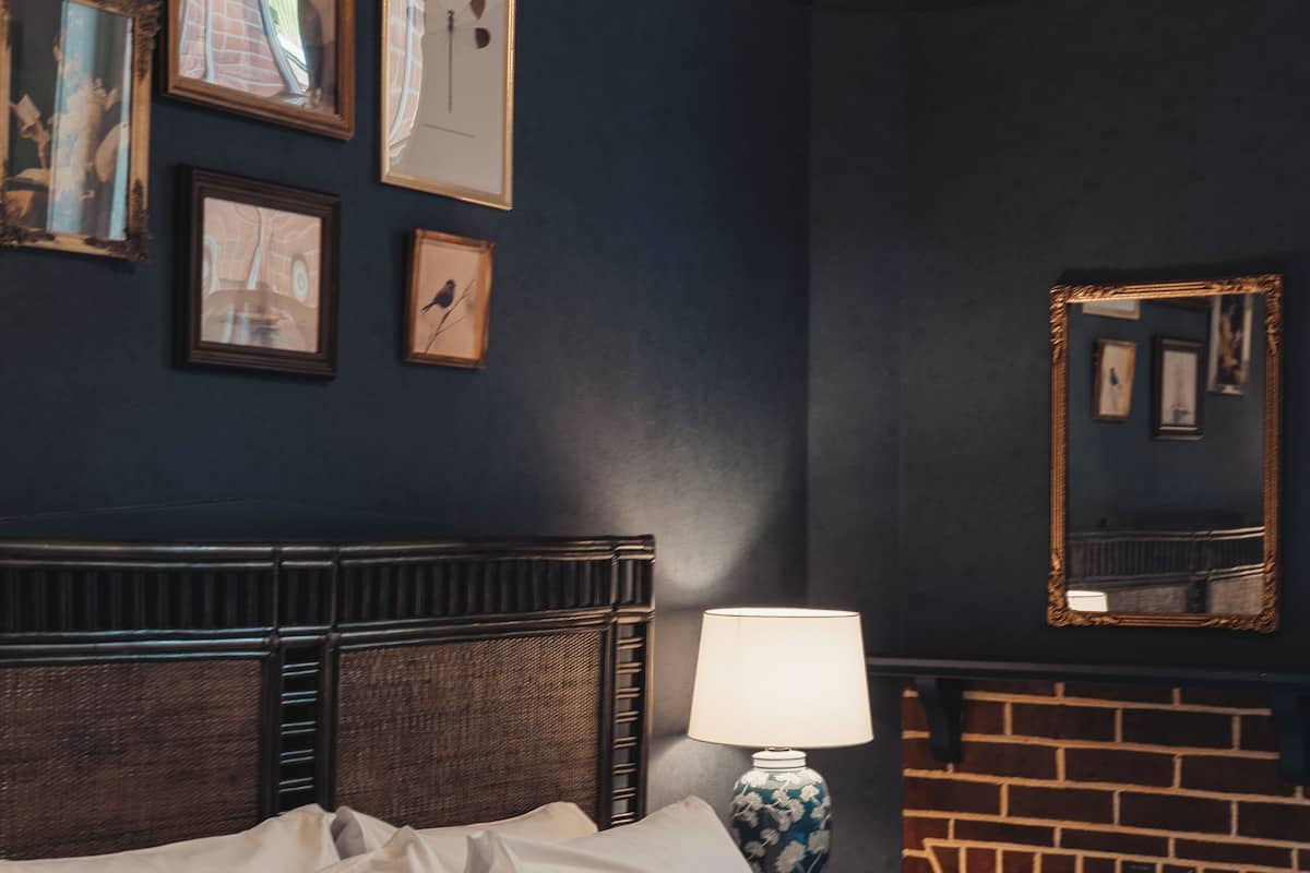 Ein ordentlich bezogenes Bett mit Kissen, einer Nachttischlampe und gerahmten Bildern an der Wand.