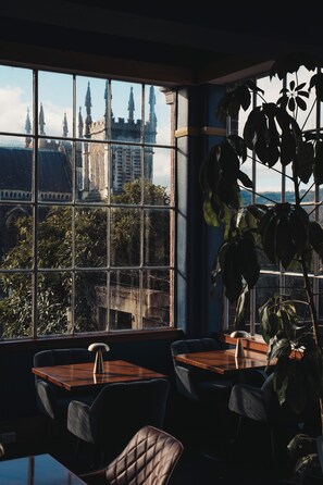 Une pièce dotée d’une grande fenêtre donnant sur un château, d’une table en bois et d’une plante en pot.