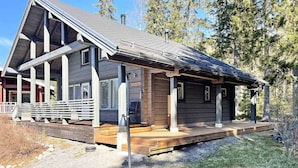 Een chalet met een houten terras, een overdekte veranda en een schoorsteen.