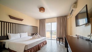 Ein Hotelzimmer mit Bett, Schreibtisch, Fernseher und Blick auf die Stadt durch große Fenster.