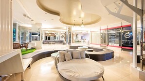 Eine moderne Hotelhalle mit einer zentralen Sitzecke, einem großen Bett und einer Reiseagentur für Thailand.