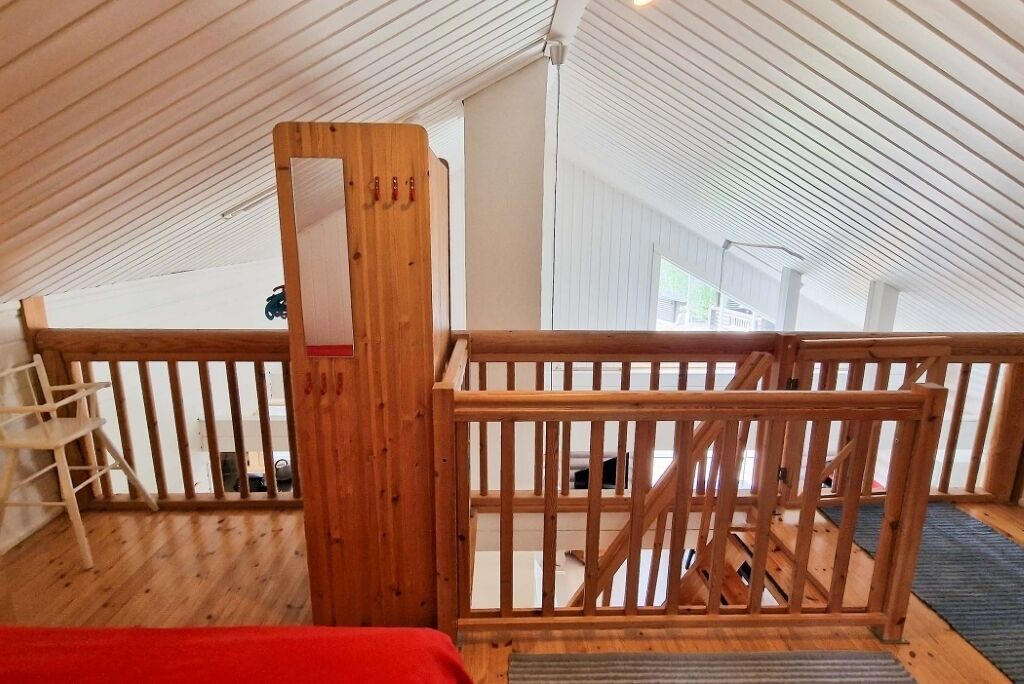 Una habitación con techos altos, barandilla de madera, una escalera y vistas a un balcón.