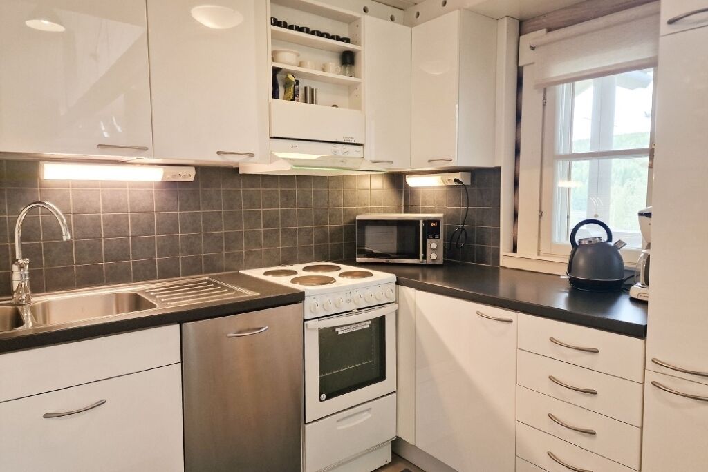 A modern kitchen with stainless steel appliances, white cabinets, and a black countertop.