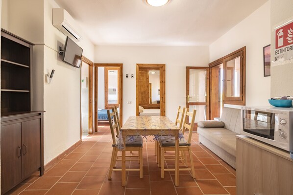 A dining area with a table, chairs, a sofa, and a microwave. - Vacation House Porto Rotondo (Porto Rotondo)