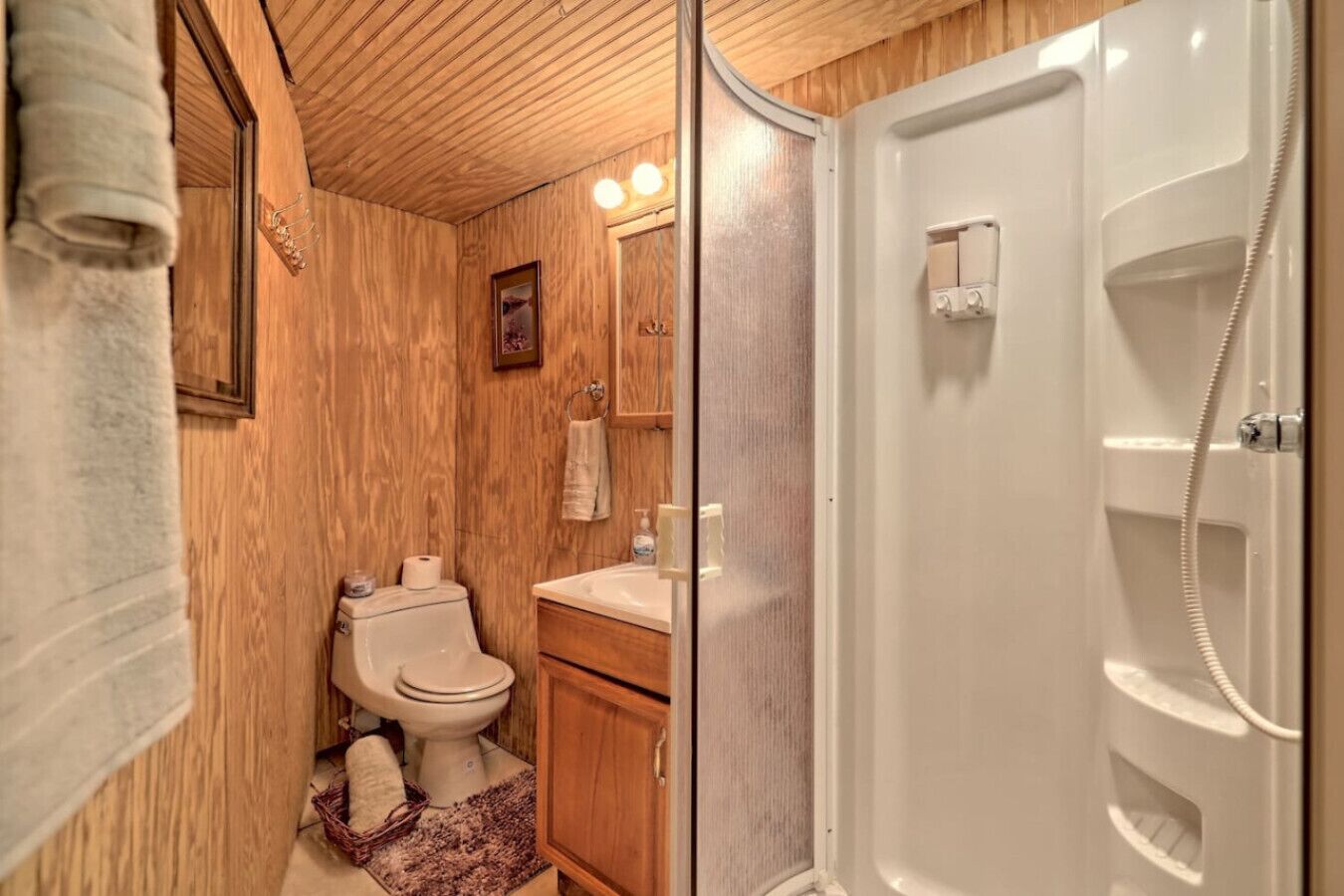 Une salle de bain en bois avec des toilettes, un lavabo et une douche.