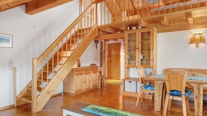 A wooden staircase leading to a loft, a dining area with wooden furniture, and a cabinet with glass doors. - Apartment Cheny with Hochschwarzwald Card (Titisee-Neustadt)