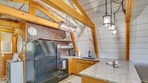 Eine Küche mit einem Edelstahlkühlschrank, Holzschränken, einer Ziegelrückwand und einer Granit Arbeitsplatte.