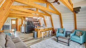 Ein geräumiges Loft mit freiliegenden Holzbalken, einer Küchenzeile und einer Sitzecke mit Sofa und Sesseln.