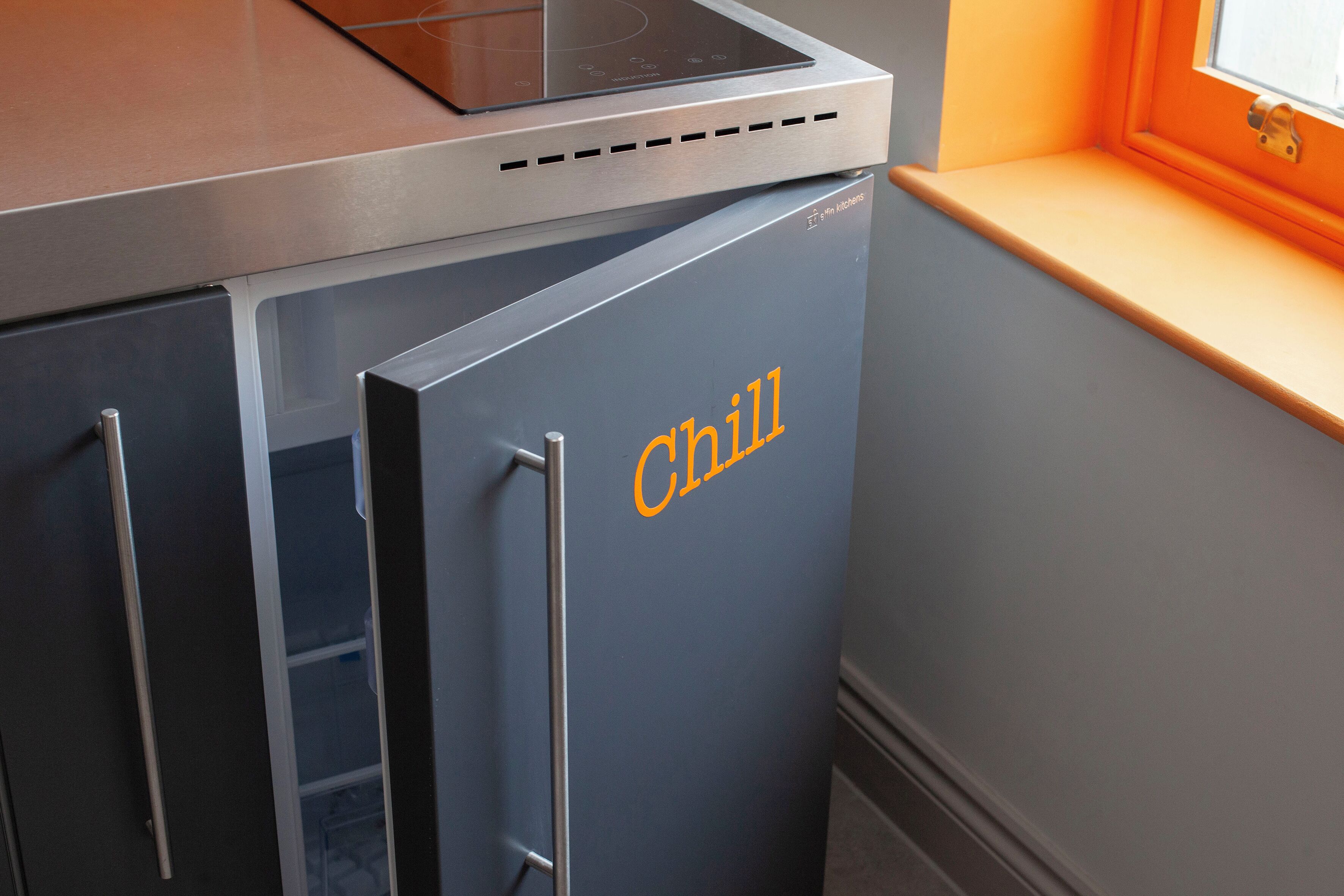 A kitchen with a built-in oven and a refrigerator labeled "Chill."