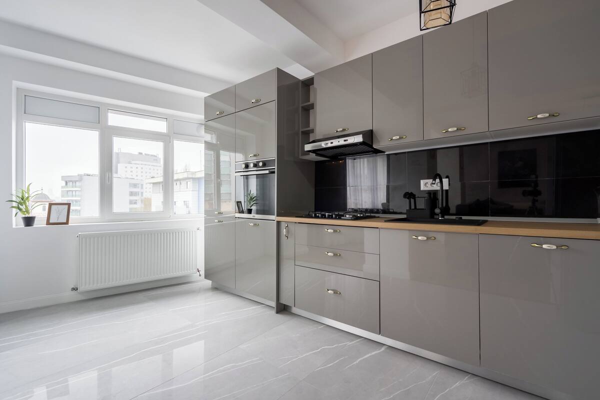 A modern kitchen with grey cabinets, a wooden countertop, and a built-in oven.