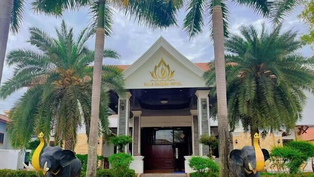 The entrance of the Dallaari Hotel with a traditional architectural style, flanked by two elephant statues and a pathway leading to the entrance. - PALA Garden Hotel (Vientiane)
