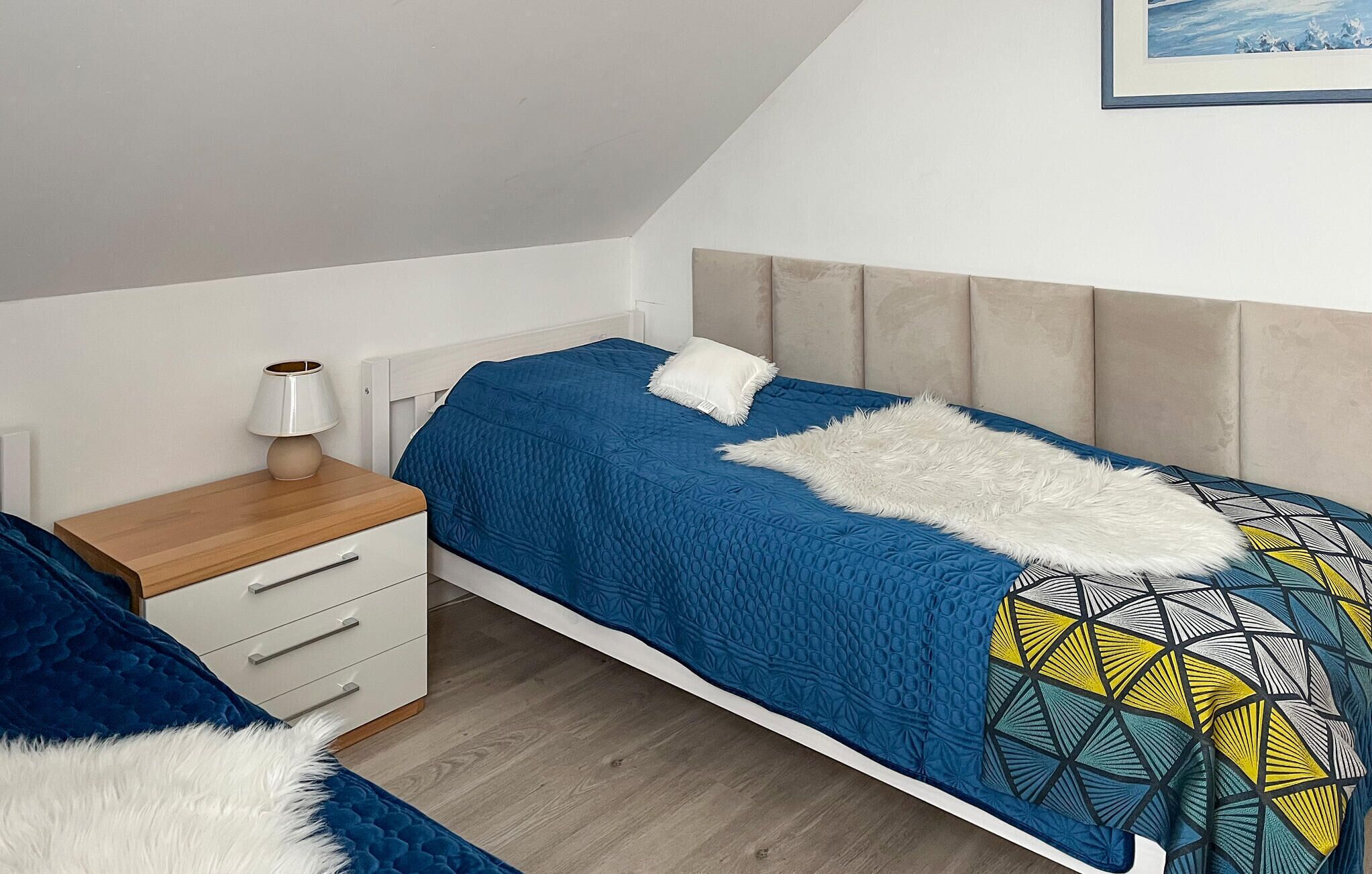 Une chambre à coucher avec un lit, une table de chevet, une lampe et un tableau encadré au mur.