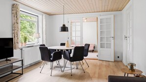 A modern dining area with a round table, four chairs, a TV, and a wooden ceiling.