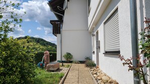 Ein Gebäude mit weißer Fassade, einem Schotterweg und einer Steinmauer.