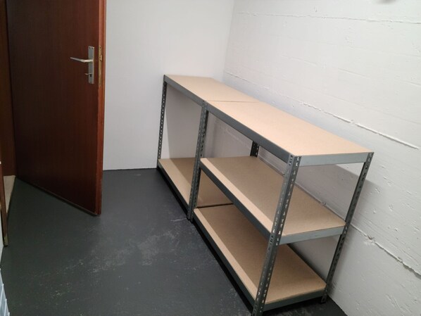 A corner of a room with a metal shelving unit against a white wall and a wooden door.