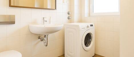 Een kleine badkamer met toilet, wastafel en wasmachine.