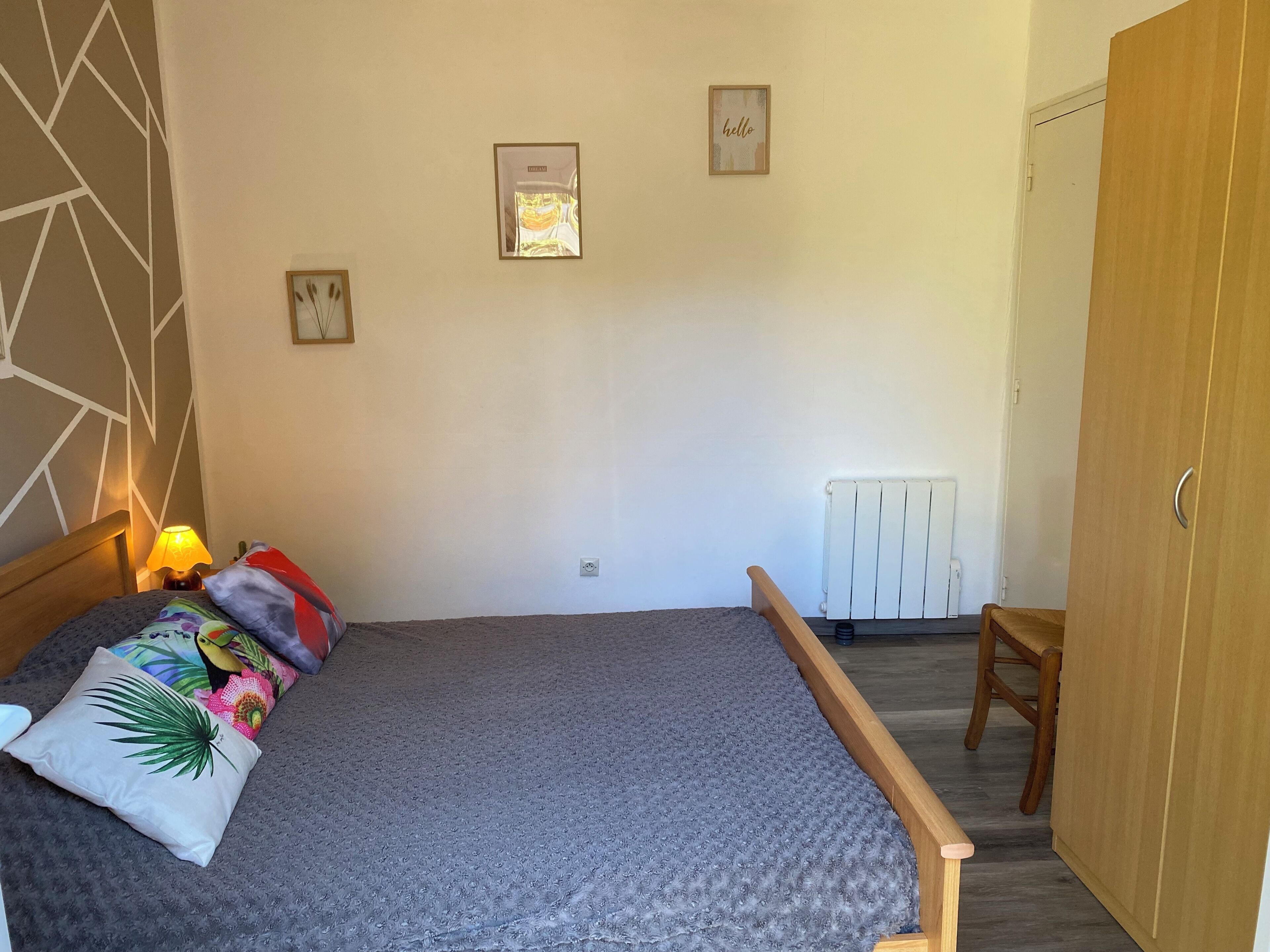 Una camera da letto con un letto, un comodino con una lampada, un termosifone e un armadio.