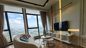 Ein modernes Wohnzimmer mit einer Couch, einem Fernseher, einem kleinen Tisch und Blick auf die Stadt.
