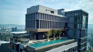 Ein modernes Hochhaus mit Pool auf dem Dach, großen Fenstern und Blick auf die Stadt.