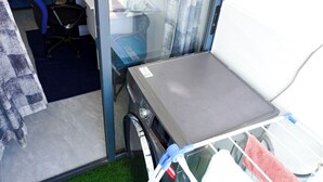 Une petite pièce comprenant une table, une chaise et une fenêtre avec des rideaux.
