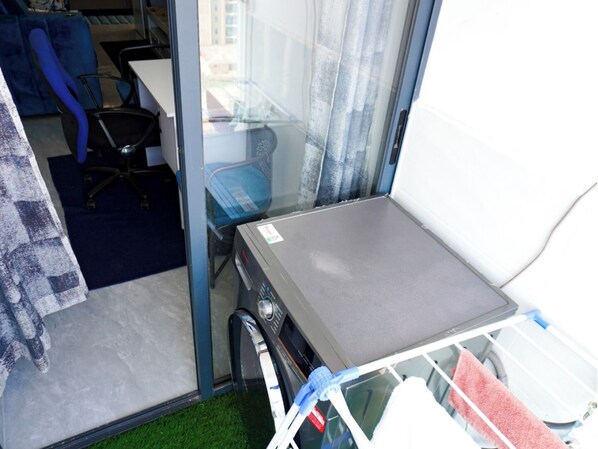 Une petite pièce comprenant une table, une chaise et une fenêtre avec des rideaux.