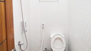Une petite salle de bain propre, équipée de toilettes, d’une douche et d’un porte-serviettes.