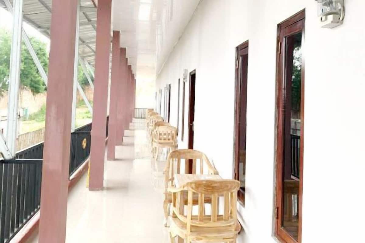 A corridor with wooden chairs, a metal roof, and a wall-mounted light fixture.