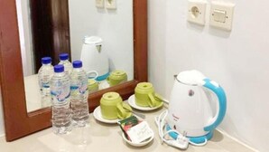 Une salle de bain équipée d’un miroir, d’un lavabo, d’une bouilloire et de bouteilles d’eau.