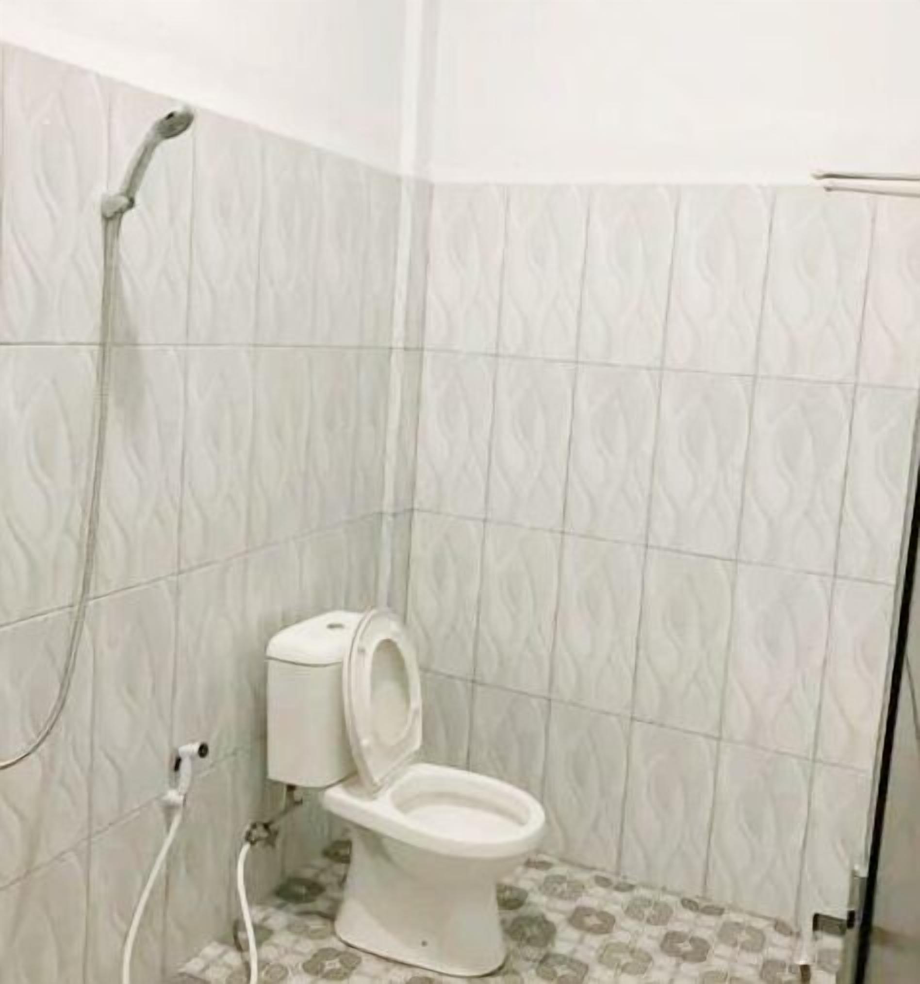 Un baño con inodoro, ducha y baldosas estampadas.