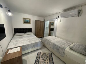 A bedroom with two beds, a wardrobe, a mirror, and a wall-mounted air conditioner. - Melanur Pansiyon (Gokceada)