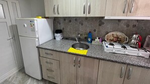 Una cocina equipada con refrigerador, lavamanos, estufa y alacenas.