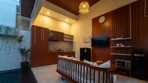 A modern living room with a wooden crib, a kitchen area, and a dining space.