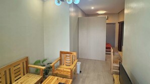 A modern living room with wooden furniture, a ceiling light fixture, and a television.