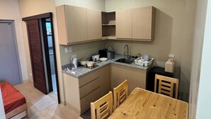 A compact kitchen with wooden cabinets, a sink, and a dining table with chairs.
