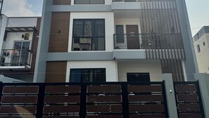 A modern multi-story building with a gated entrance, large windows, and a balcony.