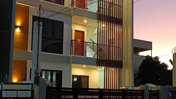 A modern multi-story residential building with balconies, a gated entrance, and a well-lit facade.