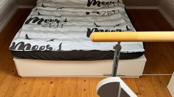 A bedroom with a bed, wooden flooring, and a sloped ceiling.