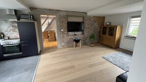 A kitchen with a stove, oven, and a dining area with chairs. - Saarner Loft Apartment with Private Terrace, Garden, and Wi-Fi (Mülheim an der Ruhr)