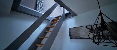 A staircase with wooden steps, a wall-mounted light fixture, and a framed quote on the wall.