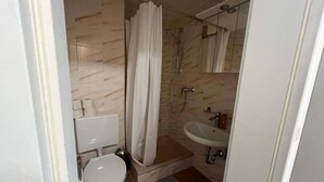A compact bathroom with a toilet, a shower with a curtain, and a sink. - Riverside Retreat in Koblenz (Koblenz)