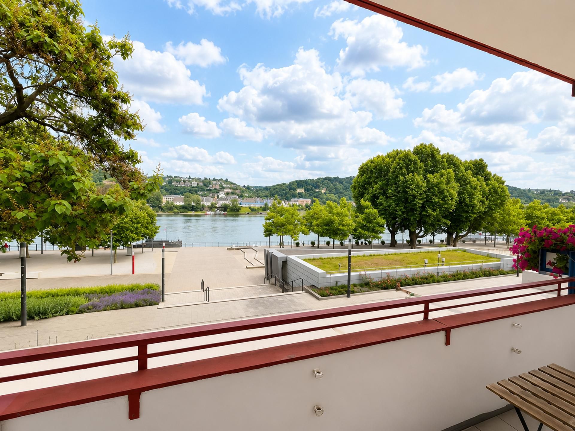 Un balcon avec vue sur une rivière, des arbres et une ville lointaine.