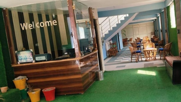 Zona de recepción con un cartel de 'Welcome', mostrador de recepción y área de espera con sillas y sofá.