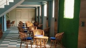 Una habitación con piso a cuadros, muebles de mimbre y pared verde.