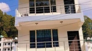 Un edificio de varios pisos con techo plano, ventanas amplias y entrada protegida por una reja.