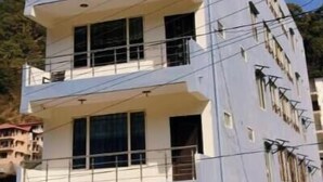 Un edificio de varios pisos con balcones y una entrada protegida por una reja.