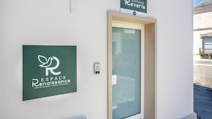 Entrada de un edificio con puerta, cartel de recepción y teclado de seguridad.