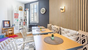 Una sala de estar moderna con un sofá, una mesa de comedor, una estantería y un ventanal.
